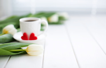 flowers and cup of coffee on wooden table. focus on flowers. copy space for congratulations or advertising. blurred cup of coffee with two red hearts.      
