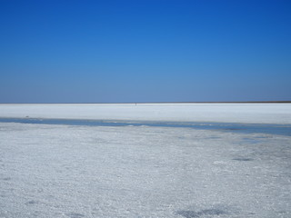 white surface of the lake covered with salt at sunrise