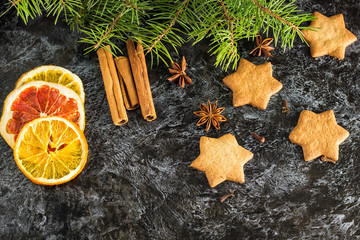Christmas background with fir tree dry orange cinnamon anise and star of Gingerbread cookies on dark background.