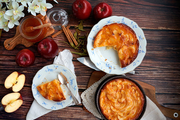 Homemade apple pie bathed with peach jam and honey. White flowers, jar of peach jam and honey. Fresh red apples and stevia leaves,