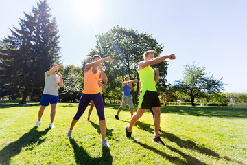 fitness, sport, martial arts, self-defense and healthy lifestyle concept - group of people or sportsmen exercising at boot camp in summer park