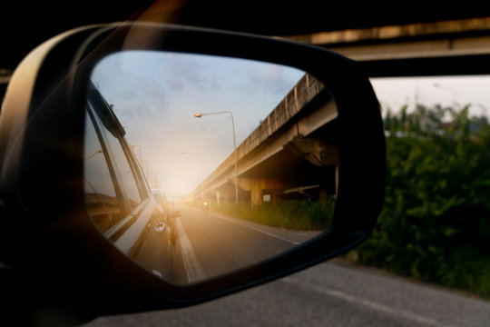 Abstract Blurred image. The view of the side of the mirror car. with empty car from behind with the bright orange light and Bridge.