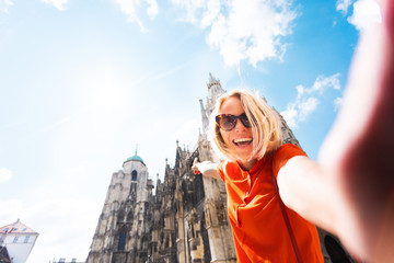 A young woman in a bright orange dress stands on the background of St. Stephen's Cathedral in...