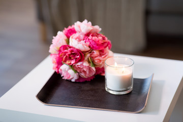 decoration, hygge and cosiness concept - burning fragrance candle and flower bunch at cozy home