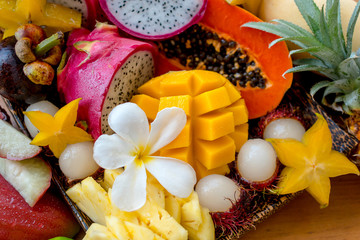Juicy ripe tropical Thai fruits on a wooden dish.