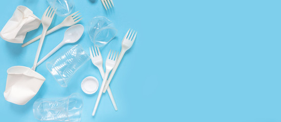 Fototapeta na wymiar Set of plastic utensils glasses, forks, spoons on a blue background, flat lay. Concept collection of recycling plastic waste recycling. Ecology environmental care.Banner