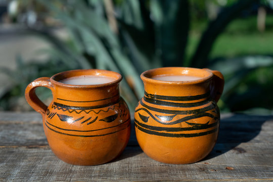 Mexican fermented beverage called "Pulque" in clay cups with agave cactus