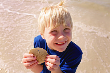 Cute Happy Little Kid on Beach who Found a Sand Dollar in Ocean