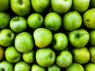 Background of green apples in the market. Ripe fruits on the counter.