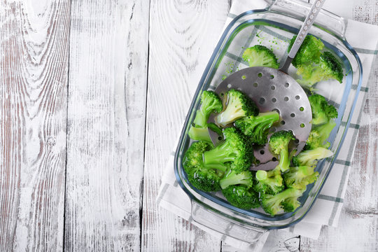 Blanched broccoli cabbage cooling down in cold water in a glass dish on white table