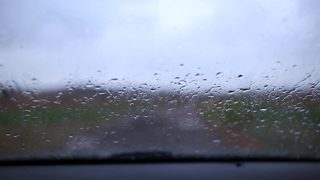 Raindrops on the car glass. Blurry silhouette. Wet car window. Close up rain drop