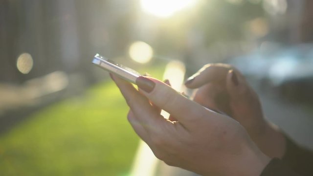 close up woman hand holding white telephone smart phone golden sun light sunshine background sunny day internet searching application store notification weblink online video call