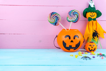 Trick or Treat - Halloween jack o' lantern, candy and rainbow lollipop on pink and blue wooden background with copy space for text. Flat lay, top view