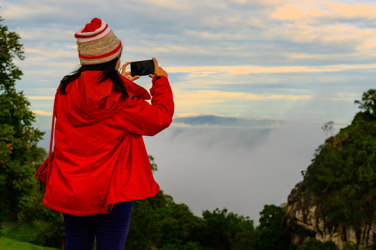 traveller woman enjoy taking photo by mobile phone at sunrise on the peak of mountain