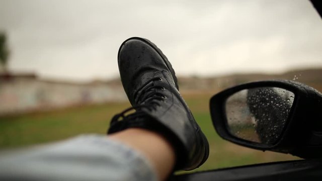 Black boot through the car window. Mirror seen through the glass. Wet car window. Close up rain drop. Car view see the mirror. Rainy day.