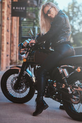 Naklejka na ściany i meble Portrait of beautiful woman in sunglasses and leather clothing on the motorbike.