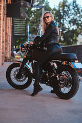 Plakat Portrait of beautiful woman in sunglasses and leather clothing on the motorbike.