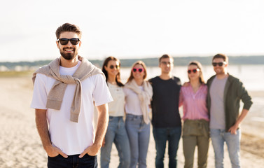 friendship, leisure and people concept - happy man with group of friends on beach in summer