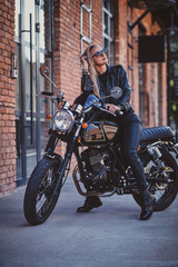 Fototapeta na wymiar Stylish mature female is posing on photographer on her new shiny retro bike.