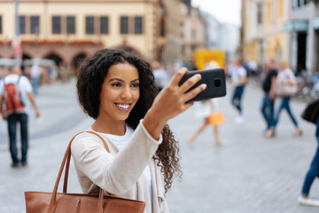 Young African woman taking a selfie in town