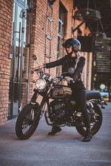 There are sexy mature woman in sunglasses and black protective helmet on the her motorbike.