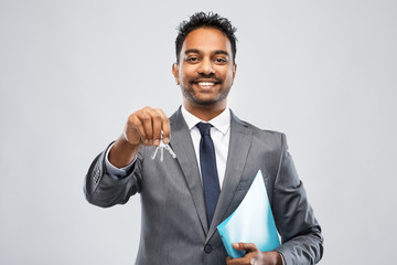 real estate business and people concept - indian man realtor with key and folder over grey background