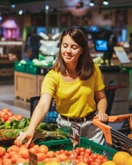 woman choosing red tomatoes from store shelf grocery shopping