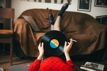 Retro woman listening music and holding a vinyl in her hands.
