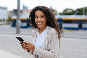 Young woman holding her mobile in an urban street
