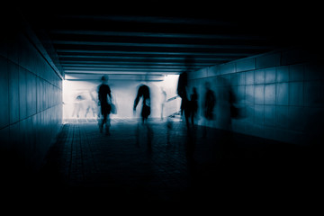 People silhouettes in the dark urban tunnel.