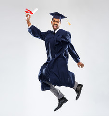 education, graduation and people concept - happy smiling indian male graduate student in mortar...