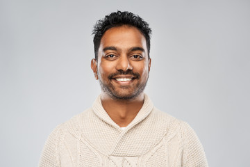 Obraz premium emotion, expression and people concept - smiling indian man in knitted woollen sweater over gray background