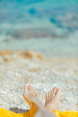 Fototapeta na wymiar woman legs on yellow blanket at sunny beach close up