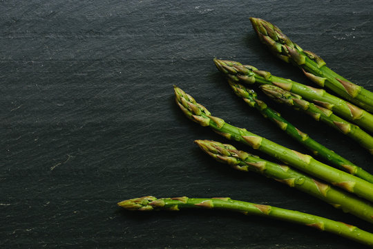 A close up shot of fresh asparagus on a gray slate countertop
