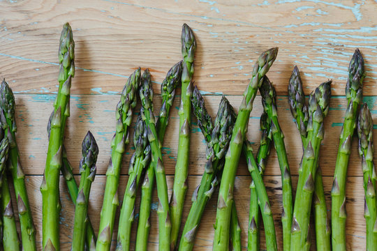 A row of fresh cut asparagus laying on a rustic farm table