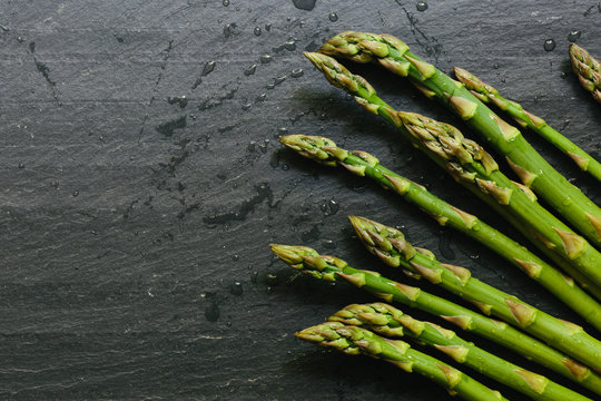 Close up of fresh picked asparagus tips on black slate countertop