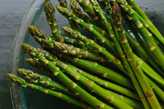 Close up of bowl of fresh picked asparagus on slate countertop