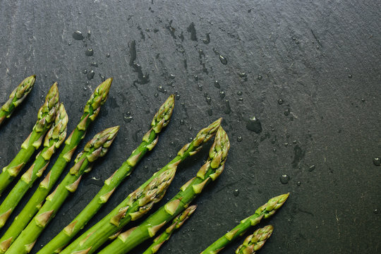 Fresh picked asparagus tips on black slate countertop