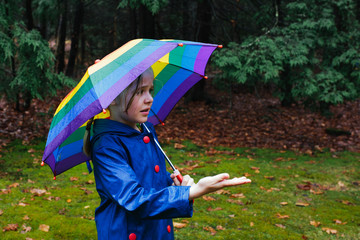 Young girl with umbrella feeling the rain on her palm