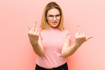 young pretty blonde woman feeling provocative, aggressive and obscene, flipping the middle finger,...