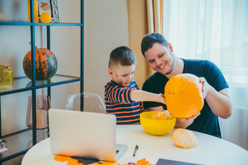 young father with toddler son making jack pumpkin head for halloween holiday