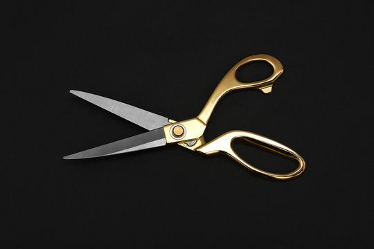 Gold tailor scissors on black background, top view