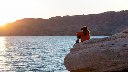 person sat down with a VR head set on looking over a lake at sunset