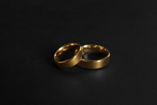 Elegant gold wedding rings on black background