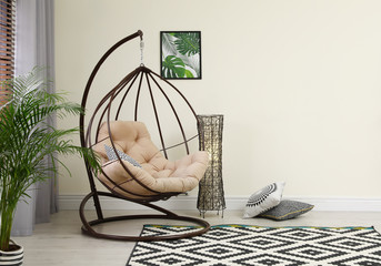 Comfortable swing chair with pillows in room interior