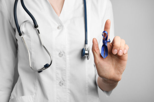 Doctor with blue awareness ribbon on finger, closeup. Symbol of medical issues