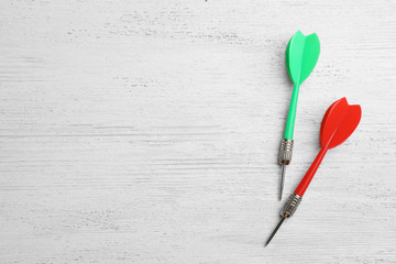 Plastic dart arrows on white wooden table, flat lay with space for text