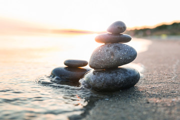 Fototapeta na wymiar Dark stones on sand near sea at sunset. Zen concept