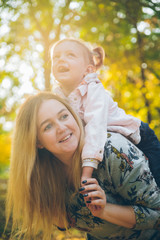 piggyback mother playing with daughter at autumn city park