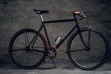Plakat Black retro bicycle is parked at photo studio on the dark background.